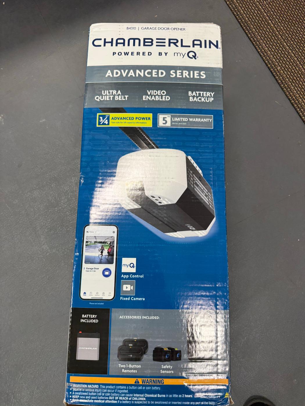 Box for a Chamberlain B4310 garage door opener photographed on a garage floor.