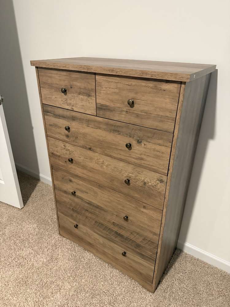 Six-drawer wood-look dresser assembled in Fuquay-Varina, standing beside a wall.
